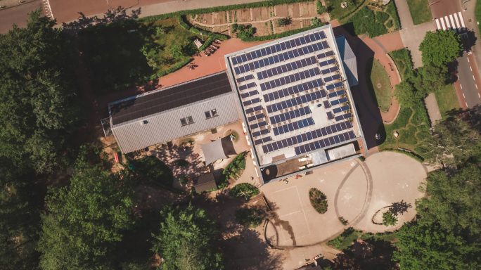 Vue aérienne d'une maison moderne avec panneaux solaires et aménagement paysager.